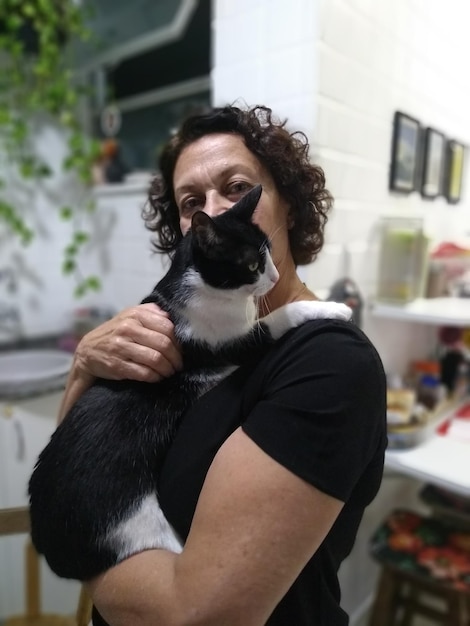 Portrait of senior woman holding cat while standing at home