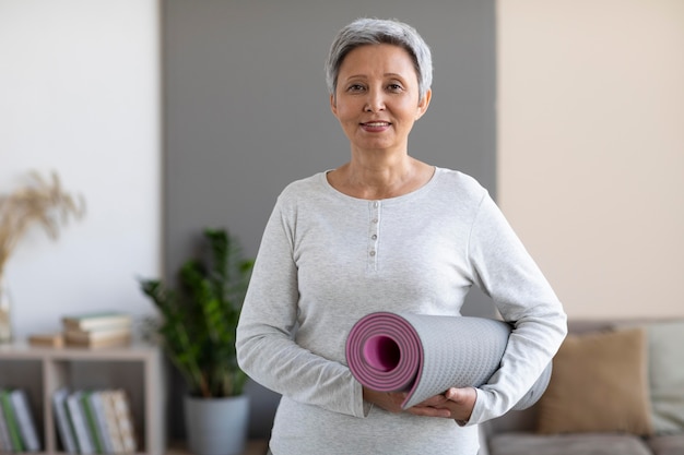 Portrait of senior woman holding yoga mat