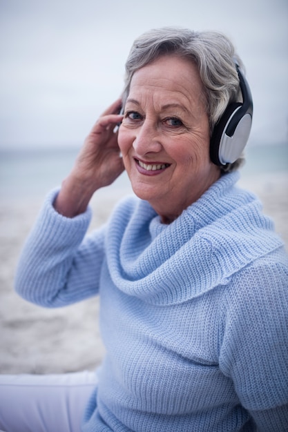 Ritratto della donna senior che ascolta la musica sulle cuffie