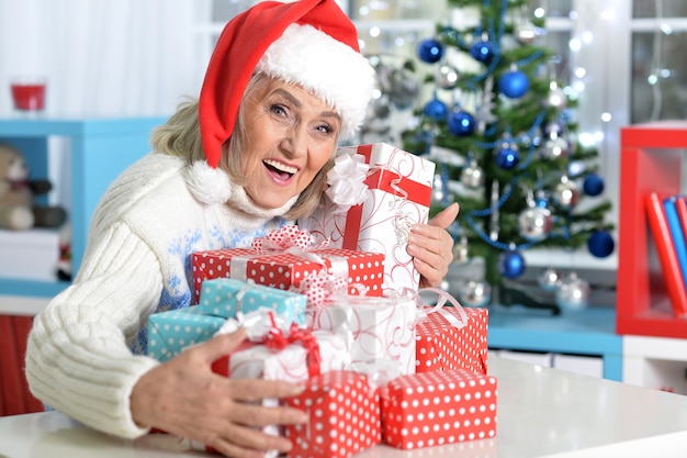 Portrait of senior woman in Santa hat with presents