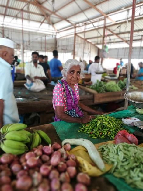 Foto ritratto di una donna anziana che vende verdure al mercato