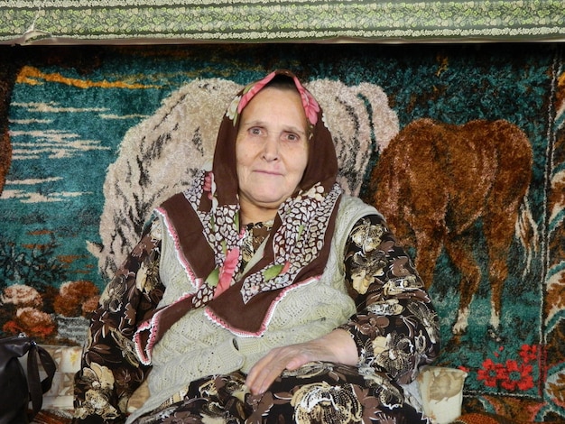 Photo portrait of senior woman sitting against paintings on wall