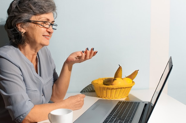 Portrait of a senior woman using laptop. Elderly woman talking by video link. Video call concept, new normal, self-isolation