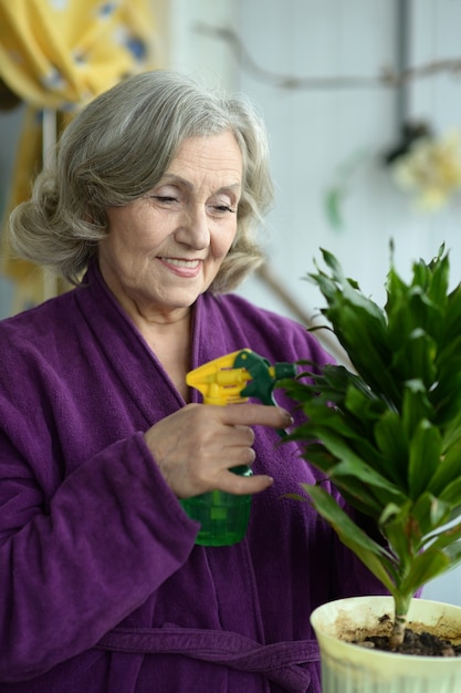 自宅で植物に水をまく年配の女性の肖像画