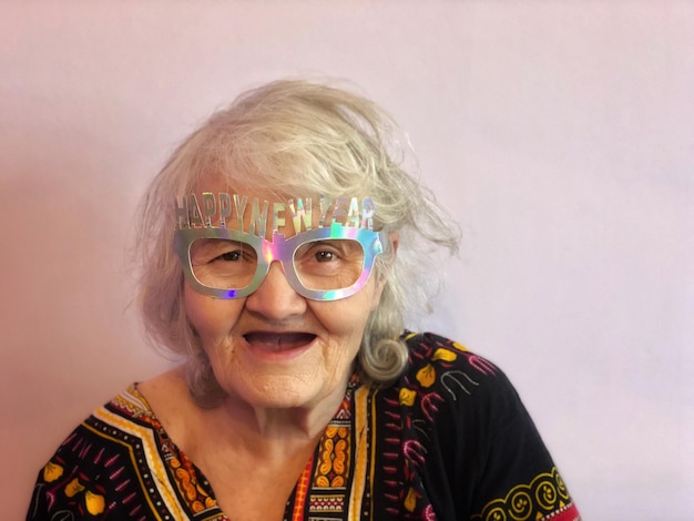 portrait of senior woman wearing novelty glasses against wall