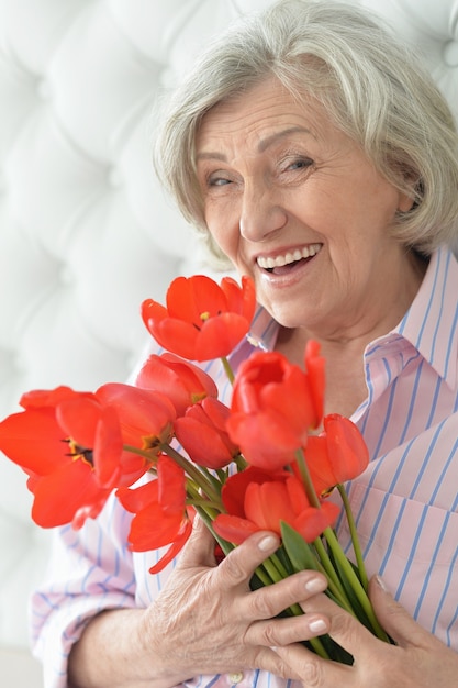 Portrait of a senior woman with blooming poppies