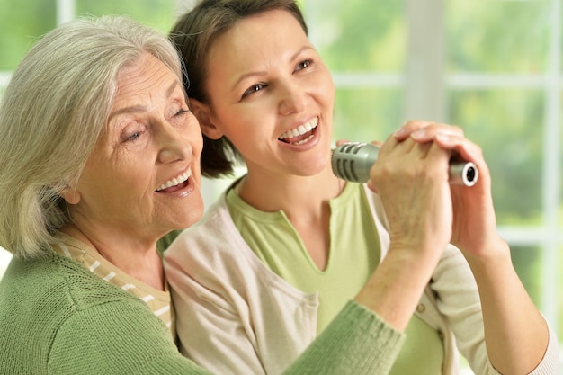 Portrait of Senior woman with daughter singing on microphone at home