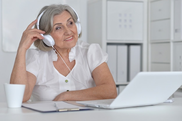 Portrait of a senior woman with headphones and laptop