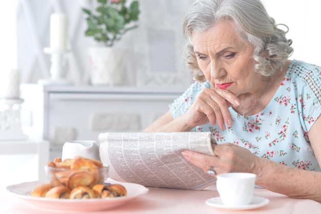 自宅で新聞を持つ年配の女性の肖像画