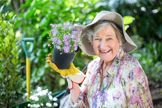 Ritratto della donna senior con la pianta in vaso in giardino