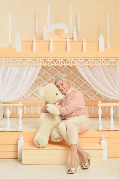 Portrait of senior woman with teddy bear at home