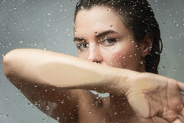 Portrait of sensual woman captured through wet glass