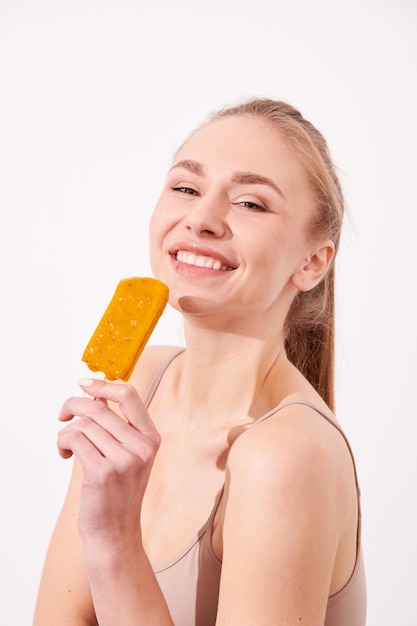 Foto ritratto di giovane bella donna di sensualità che mangia il gelato dolce giallo