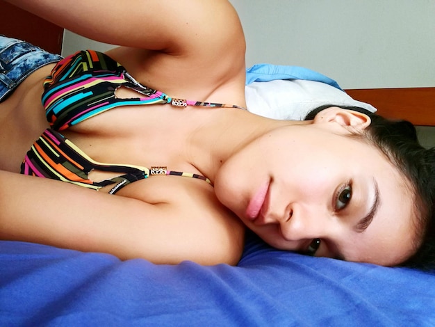 Portrait of sensuous woman lying down on bed at home