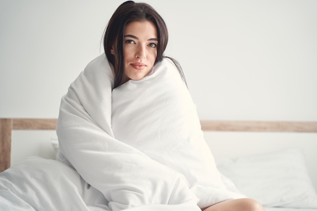 Photo portrait of a serene pretty woman wrapped in a duvet looking in front of her