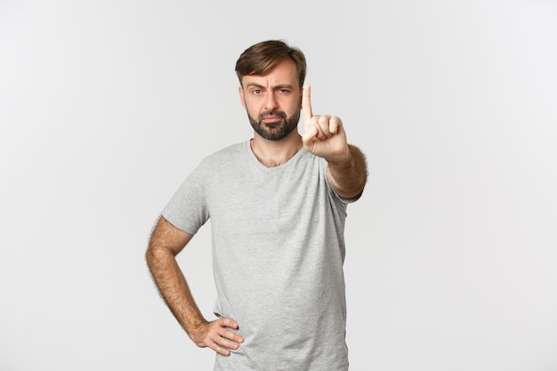 Portrait of serious adult man with beard, wearing gray t-shirt