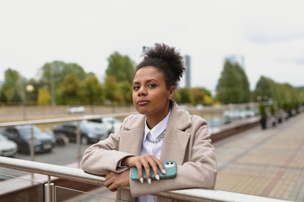 Portrait of a serious african american woman with a mobile phone on the background of the city