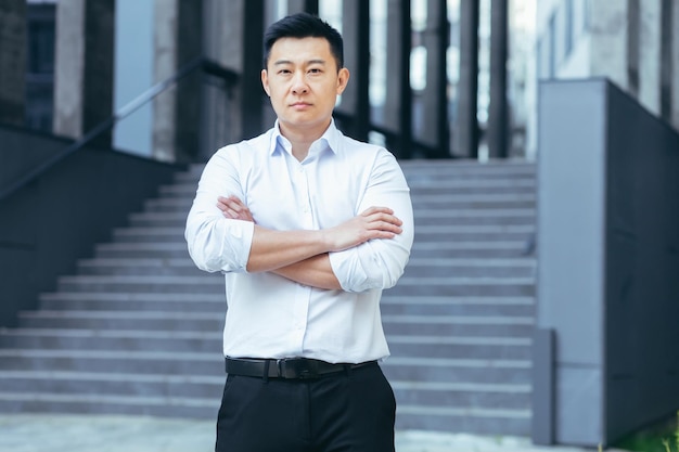 Портрет серьезного азиатского бизнесмена за пределами офиса, смотрящего в камеру