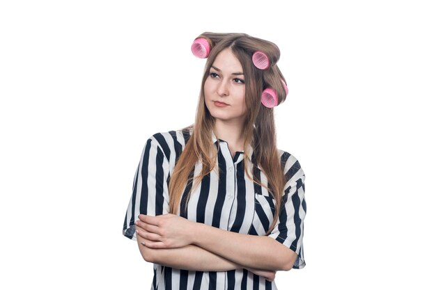 portrait of a serious business woman in a striped shirt with hair curlers on her head with arms crossed isolated on white background