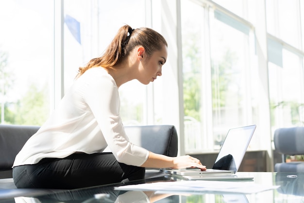 Photo portrait of a serious businesswoman using laptop in office.