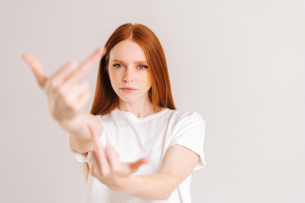 Portrait of serious calm young woman showing middle fingers on\
both arms gesture of disrespect and hate doing bad expression rude\
and rude female showing middle finger looking at camera