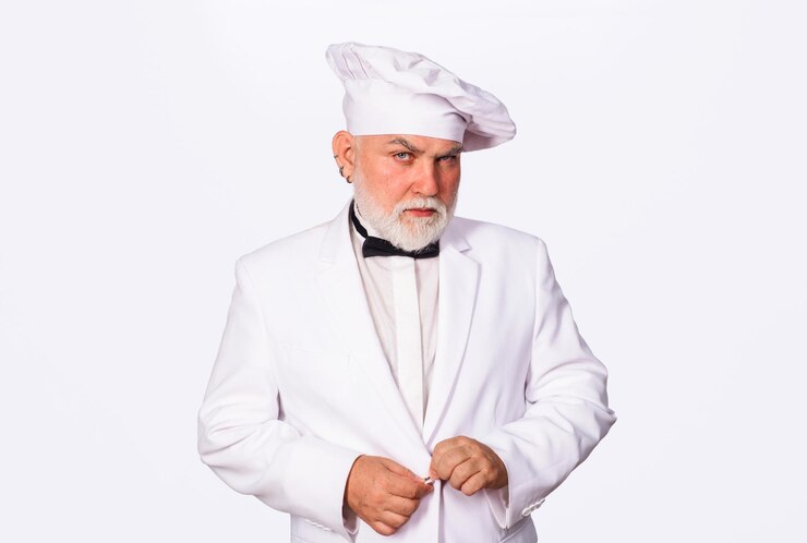 Photo portrait of serious chef in uniform bearded cook or baker man in kitchen restaurant and hotel confident male cook in white uniform and chef hat professional culinary cooking and food preparation