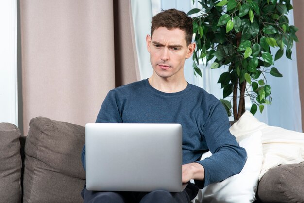 Portrait of serious concentrated guy young handsome man freelancer is working on his laptop pc