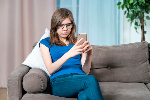 Portrait of serious concentrated teen girl young beautiful woman in glasses holding in hands looking