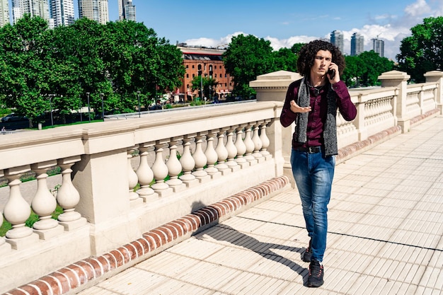 Portrait of a serious curly-haired young latin man walking down a sidewalk