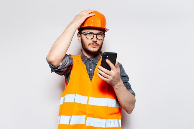 Portrait of serious engineer talking on smartphone on white background