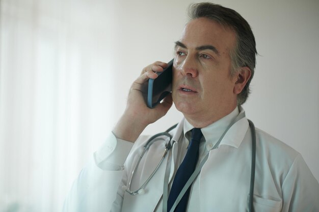 Portrait of serious general practitioner talking on phone