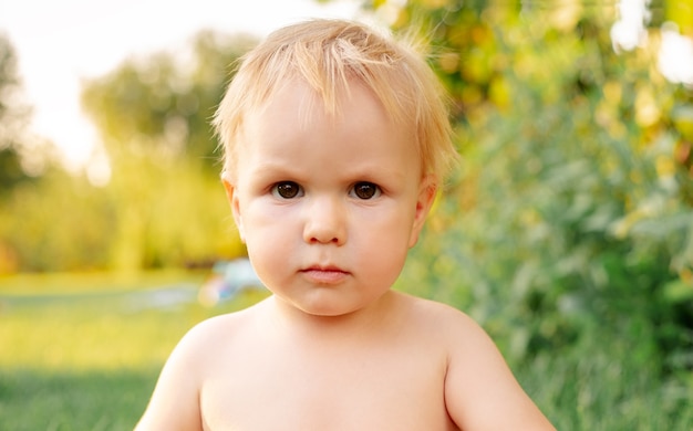 Portrait serious kid boy. Portrait blond kid boy outside. Happy childhood