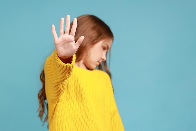 Portrait of serious little girl showing stop gesture warning to go looking away dissatisfied