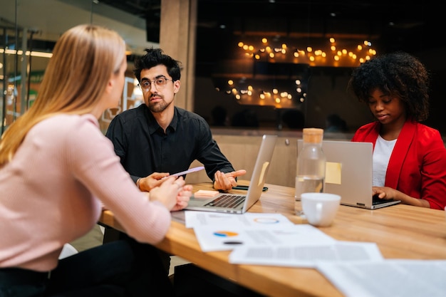 Portrait of serious male boss manager sharing knowledge with new female colleague explaining problem solution or helping with online project