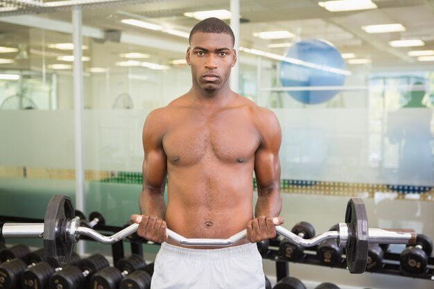 Portrait of serious man lifting barbell in gym