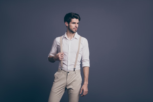 Portrait of serious minded guy rich wealthy millionaire attract woman ideal man concept touch his suspenders stare copy space wear classy outfit .