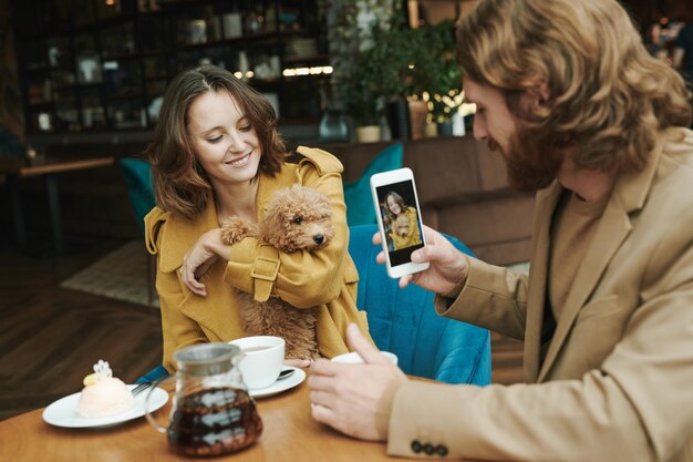 Portrait of serious modern guy with beard sitting at round\
table in loft cafe and calling by mobile