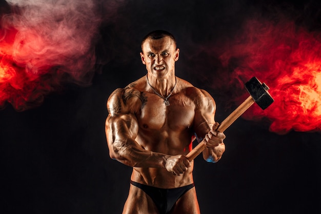 Portrait of serious muscular topless man with sledgehammer