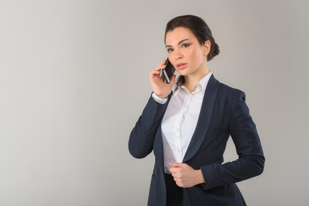 Portrait of serious pretty businesswoman talking on the phone in modern office