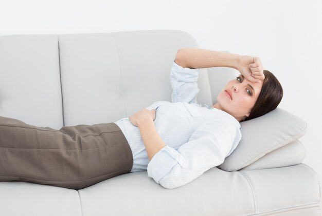 Portrait of a serious well dressed woman lying on sofa