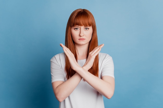 Portrait of serious woman holding two arms crossed gesturing no sign isolated on blue background