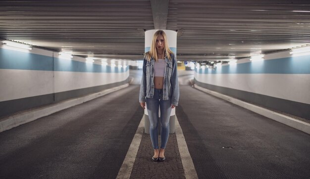 Photo portrait of serious woman standing under illuminated tunnel