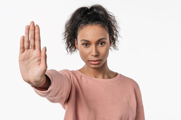 Photo portrait of serious young african woman showing stop gesture with her palm