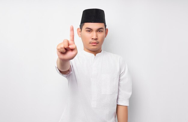 Photo portrait of serious young asian muslim man showing stop gesture with angry expression isolated on white background people religious islamic lifestyle concept