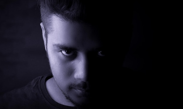 Portrait of serious young man against black background