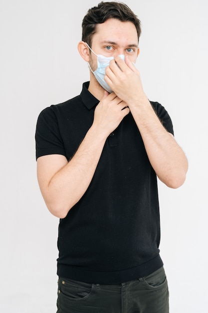 Portrait of serious young man in medical mask wearing casual black shirt