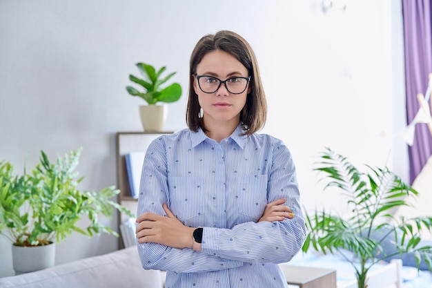 Portrait of serious young woman looking at camera with crossed arms