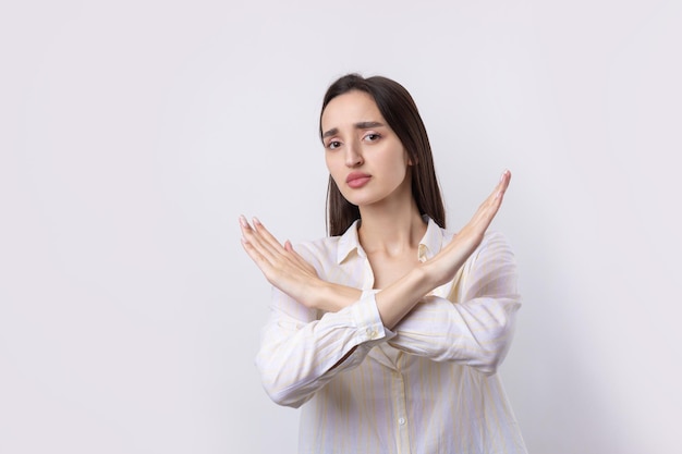 Foto ritratto di una giovane donna seria che mostra il gesto di fermarsi con il palmo della mano su uno sfondo bianco