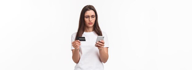 Portrait of seriouslooking focused young attractive woman copying digit numbers from credit card int