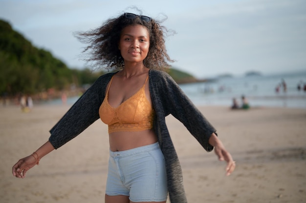 Ritratto sexy signora asiatica africana in piedi e rilassante in spiaggia l'ora legale al mare e in spiaggia